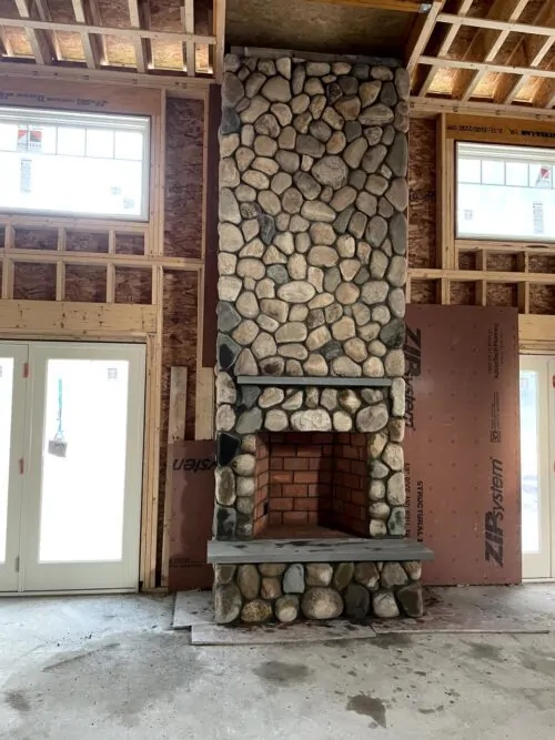 Floor-to-ceiling river rock fireplace built by JS Masonry