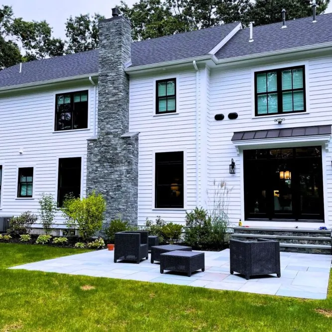Bluestone patio and stone veneer chimney installation in Massachusetts