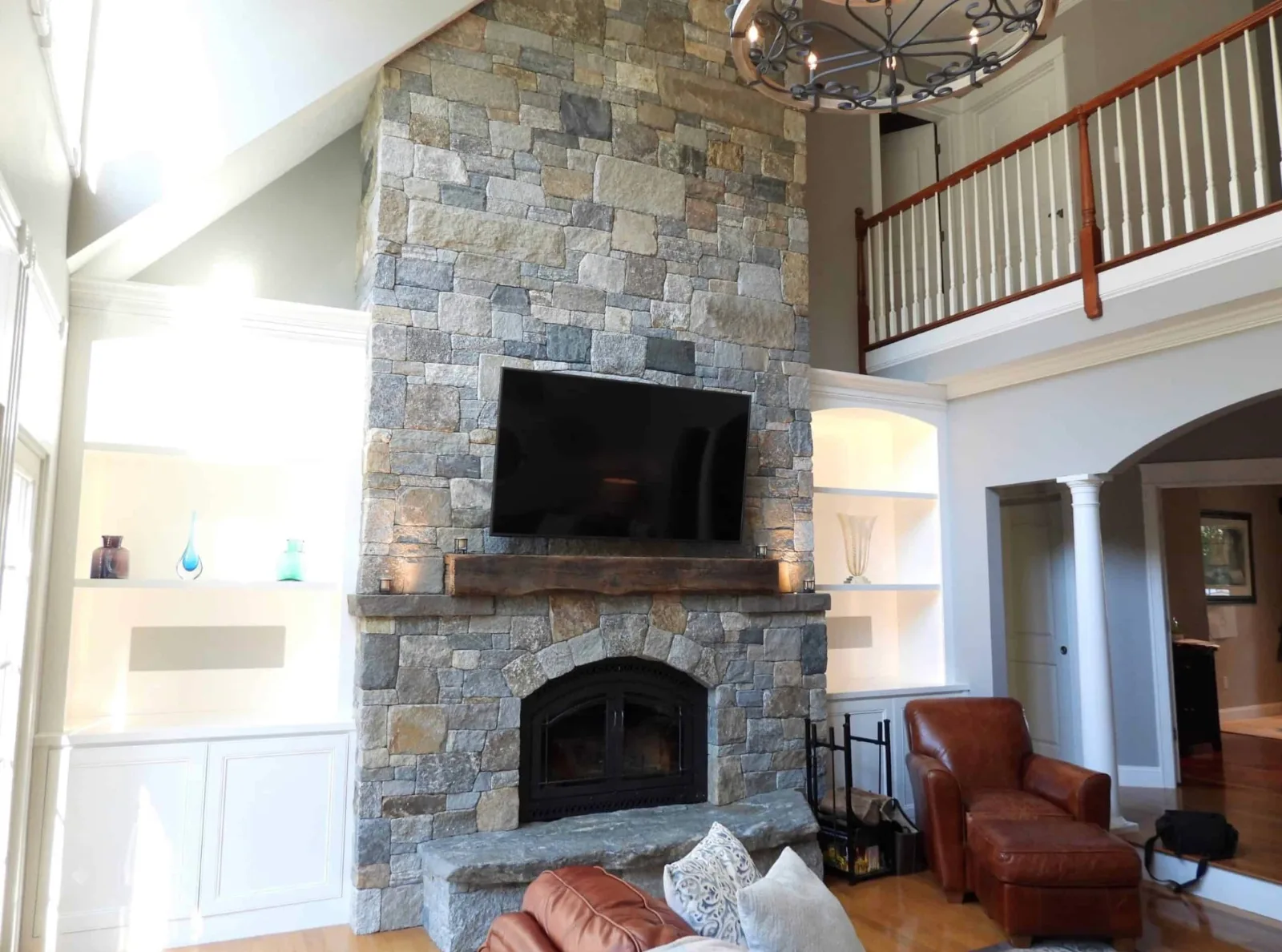 Floor-to-ceiling stone fireplace with an arched opening, raised hearth and wooden mantel