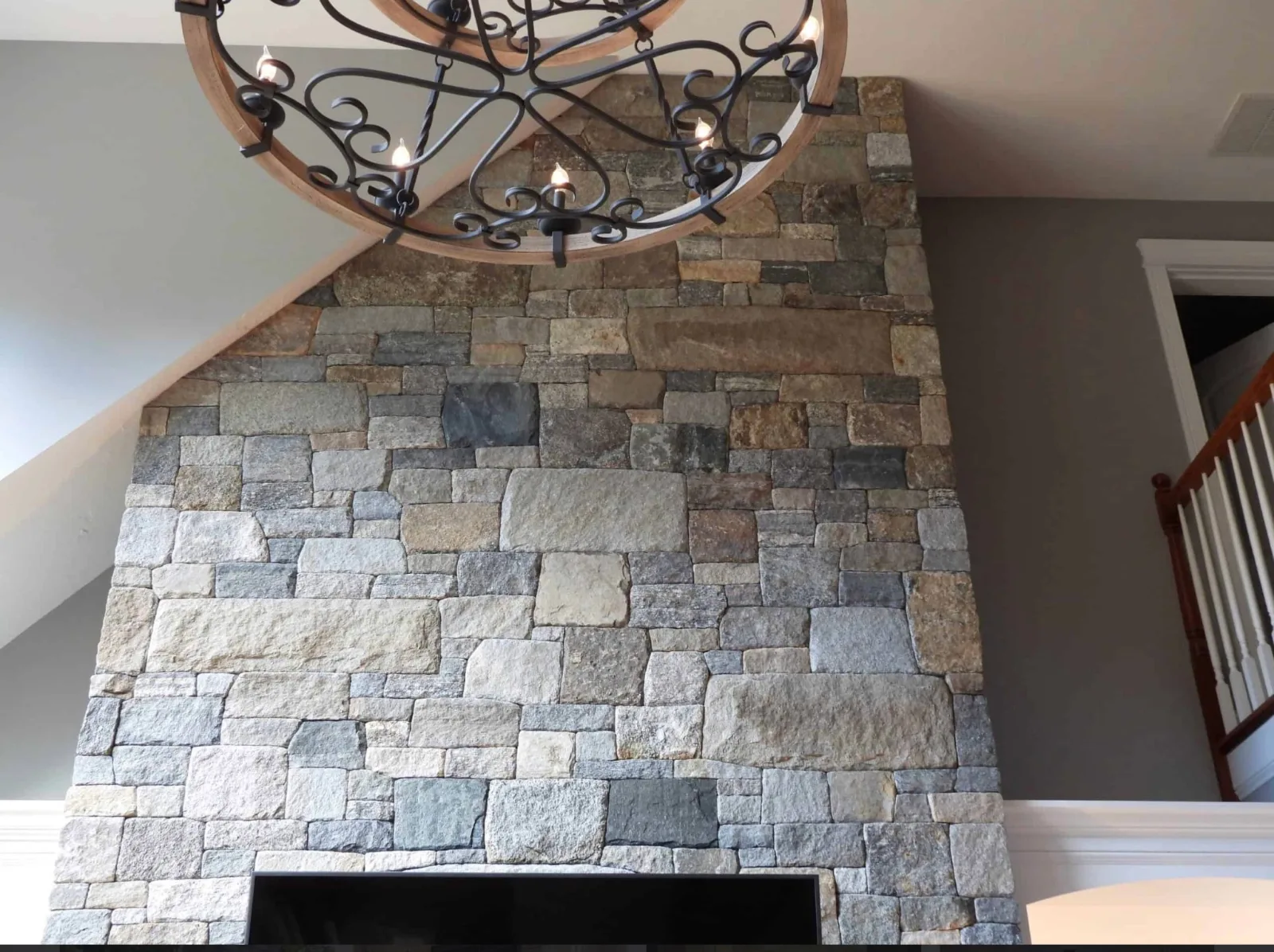 Gray and tan rectangular stone cladding above an indoor fireplace beneath a sloped ceiling