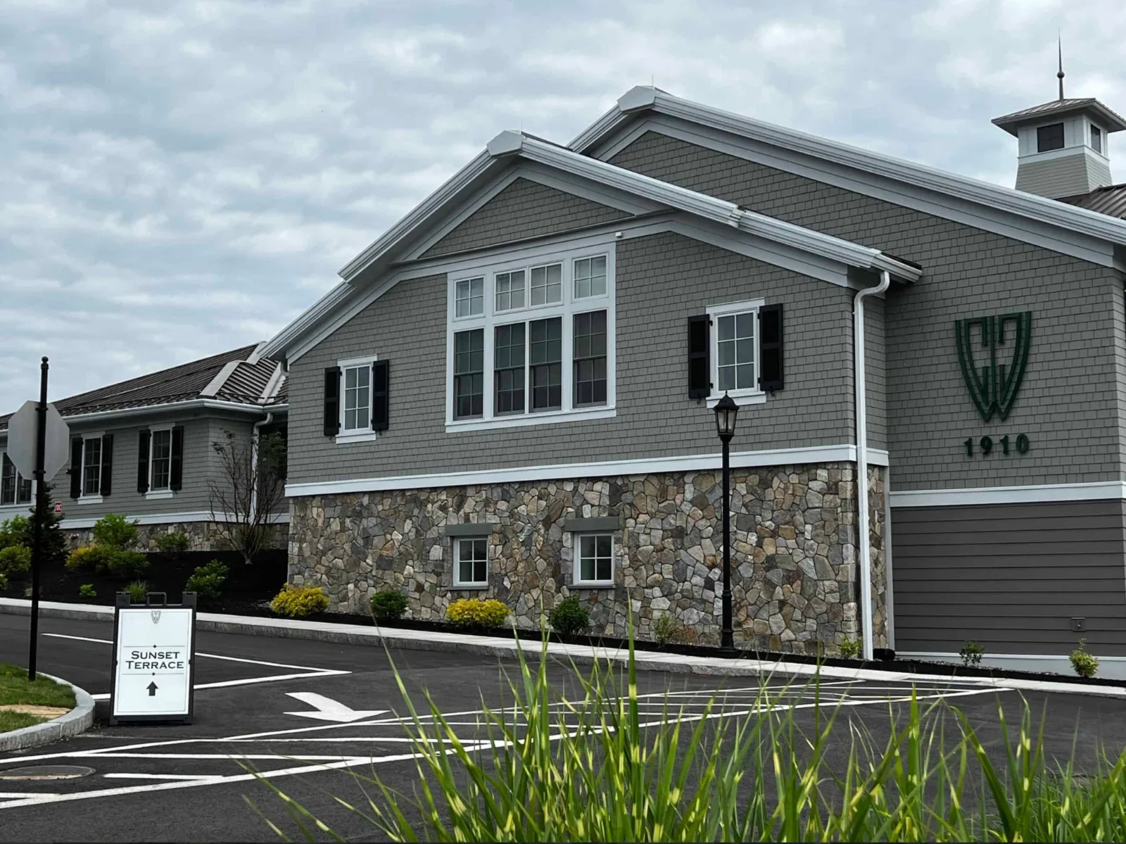 Irregular stone cladding along the lower facade of a gray building beside a parking area